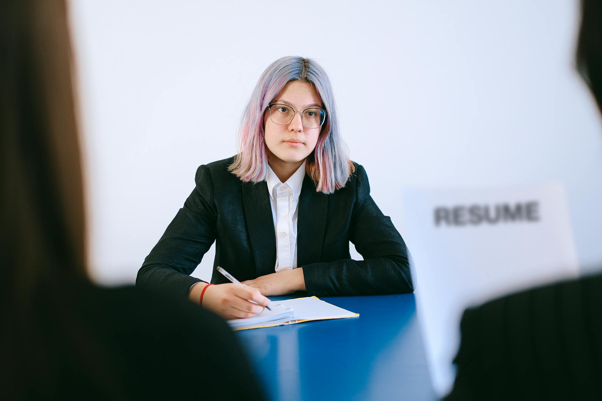 A young woman in a suit during a job interview, writing notes.