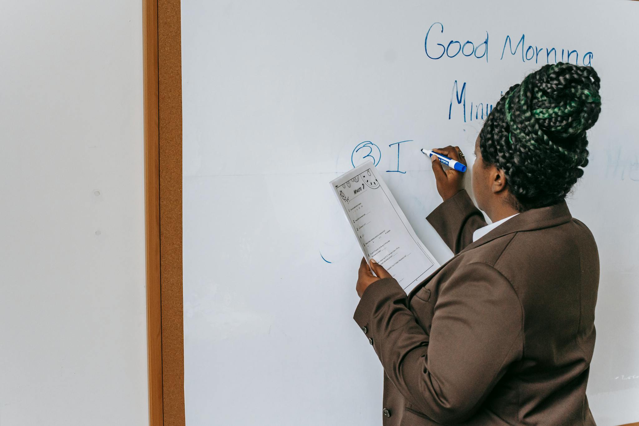 Back view anonymous African American female teacher wearing formal suit writing information on paper in auditorium