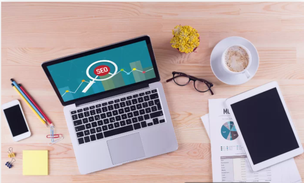 SEO content writing workspace with laptop magnifying glass and coffee cup