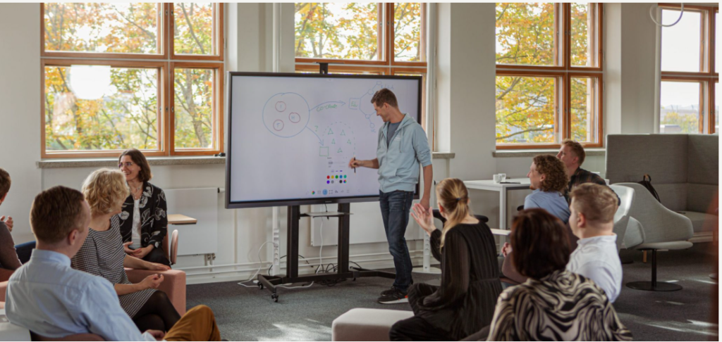 A trainer presenting in front of a group of people in a classroom or conference room