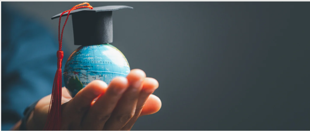 A hand holding a small globe representing global education and worldwide opportunities