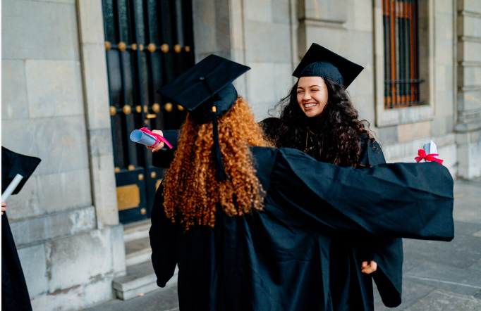 A happy female graduate wearing a cap and gown celebrating her graduation