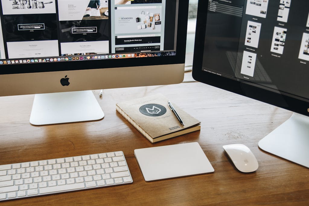Minimalist web design and development workspace with dual monitors, keyboard, mouse and notebook for productivity